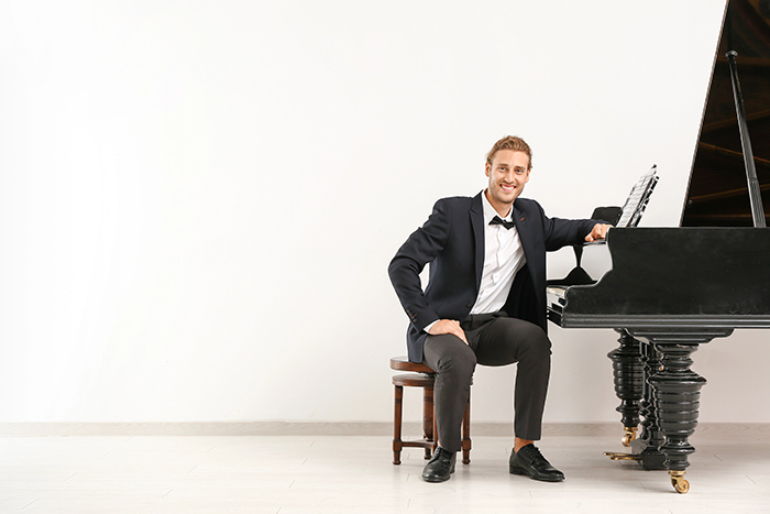 Man smiling and staring in front of piano