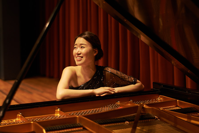 Beautiful lady smiling and sitting in front of piano