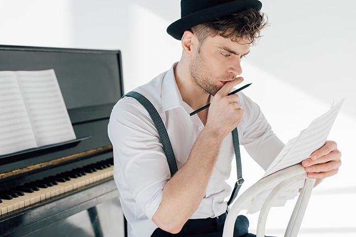 Thoughtful man holding music papers and pencil