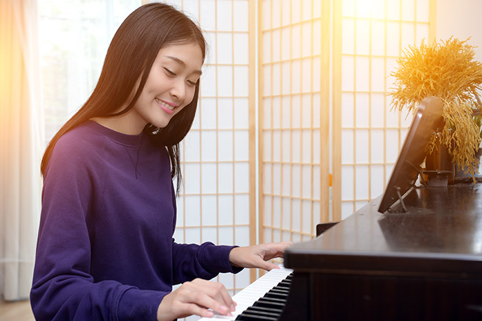 Asian lady smiling and playing piano